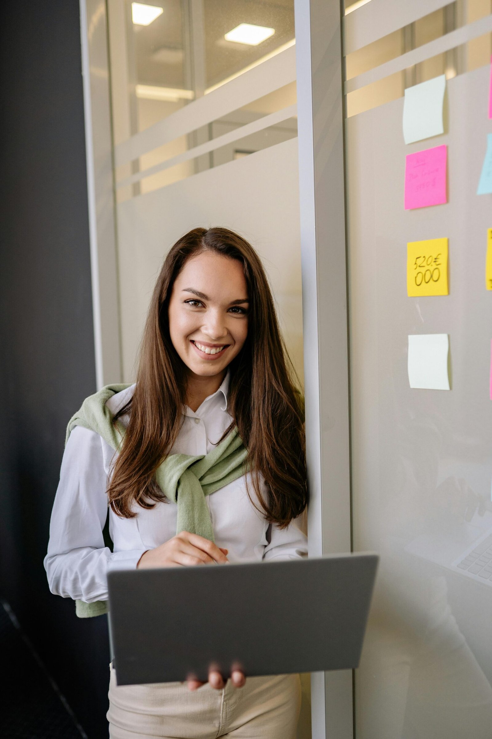Woman verifies product backlog on laptop in front of a Scrum board